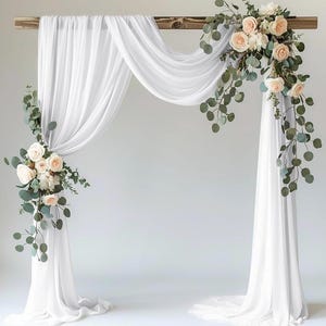 以下が含まれることがあります： 木製のアーチに、白の透き通った布がかけられています。アーチは、桃色のバラとユーカリの葉のガーランドで飾られています。
