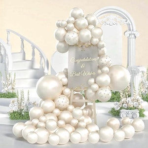 May include: White pearl balloons arranged in a decorative arch with a sign that reads "Congratulations & Best Wishes".