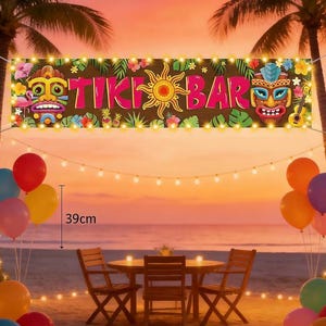 May include: A banner with the words "TIKI BAR" in pink letters, adorned with tropical flowers, sun, and tiki masks. The scene includes a beach setting with a table, chairs, balloons, and string lights. The banner is 39cm in height.