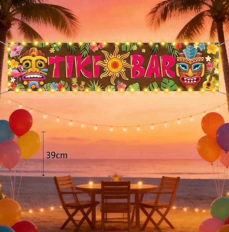 May include: A banner with the words "TIKI BAR" in pink letters, adorned with tropical flowers, sun, and tiki masks. The scene includes a beach setting with a table, chairs, balloons, and string lights. The banner is 39cm in height.