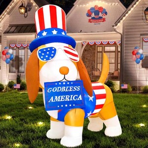 Könnte beinhalten: Eine aufblasbare Hundedekoration mit einem rot-weiß-blauen Zylinder und einer Sonnenbrille mit Sternenmuster. Der Hund hat braune Ohren und hält ein blaues Schild mit der weißen Aufschrift GODBLESS AMERICA sowie rot-weißen Streifen.