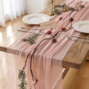 May include: A pink table runner with a natural twig garland and small decorative pumpkins. The runner is made of a soft, sheer fabric and is perfect for adding a touch of elegance to any table setting.