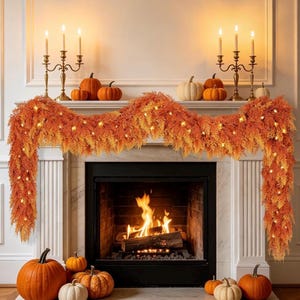May include: A fireplace mantel decorated with an orange and yellow autumn foliage garland featuring integrated warm string lights. Two gold candelabras with lit candles sit on the mantel alongside several orange pumpkins of varying sizes.