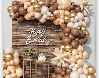 May include: A brown and beige balloon arch with gold balloons and star-shaped balloons. The arch is decorated with a wooden backdrop with the words "Happy Birthday" in white neon letters.