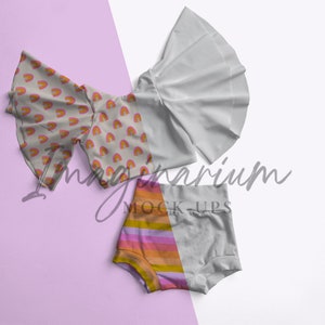 May include: Three pieces of clothing: a white ruffle top, a light gray and orange striped bottom, and a beige top with a rainbow pattern. The text "Imaginarium Mock-Ups" is visible in the image.