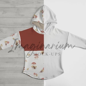 May include: A white hooded sweatshirt with a red and white mushroom pattern. The sweatshirt has long sleeves and a relaxed fit. The text "Imaginarium Mock-Ups" is printed on the front of the sweatshirt.