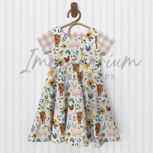 K&ouml;nnte beinhalten: Ein wei&szlig;es Kleid mit einem braunen, gelben und gr&uuml;nen Farmtier-Druck. Das Kleid hat kurze &Auml;rmel mit einem karierten Muster und einen Volant-Rock.
