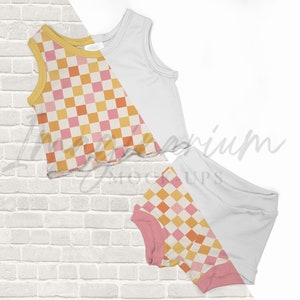 May include: A two-piece outfit for a child, featuring a sleeveless tank top and shorts. Both pieces are white with a checkered pattern in shades of pink, orange, and yellow.