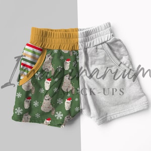 May include: A pair of green and white patterned shorts with a yellow waistband and a red and white striped pocket. The shorts are next to a pair of gray shorts with a white waistband.