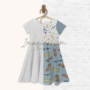 K&ouml;nnte beinhalten: Ein wei&szlig;es und blaues Kleid mit einem Skateboard-Muster. Das Kleid hat kurze &Auml;rmel und einen ausgestellten Rock. Das Kleid h&auml;ngt an einem Holzb&uuml;gel an einer wei&szlig;en Backsteinwand.