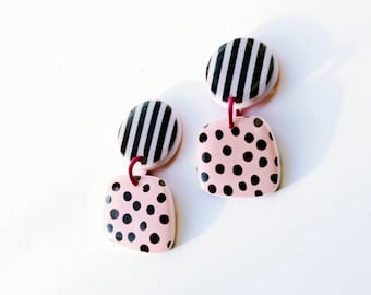 May include: A pair of pink and black earrings with a striped and polka dot design.