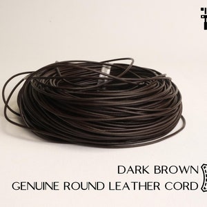 Może przedstawiać: Szpula z 2 mm okrągłym, ciemnobrązowym sznurkiem skórzanym.  GENUINE ROUND LEATHER CORD. DARK BROWN. VAV LEATHER SELLER.
