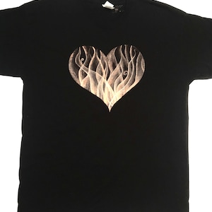Peut inclure: T-shirt noir avec un motif en forme de cœur blanc. Le cœur est rempli de lignes tourbillonnantes qui ressemblent à des flammes.