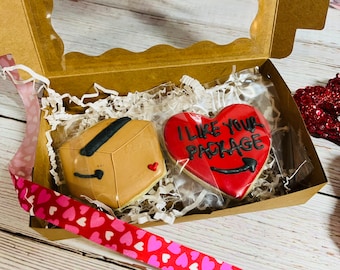 May include: A brown cardboard box and a red heart-shaped cookie with the text "I like your package" in black icing. The cookies are in a brown box with white tissue paper.