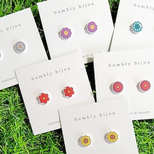 May include: Six cards with the text "bumbly bijou" and handmade flower earrings. The earrings are in various colors, including red, pink, yellow, blue, and purple.