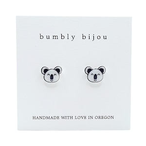 May include: A pair of white koala stud earrings with black outlines on a white card with the text "bumby bijou" and "HANDMADE WITH LOVE IN OREGON".