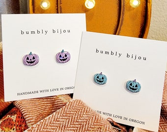 May include: Two pairs of pumpkin-shaped stud earrings. One pair is light blue and the other is light purple. The earrings are on white cards with the text "bumbly bijou" and "handmade with love in Oregon".