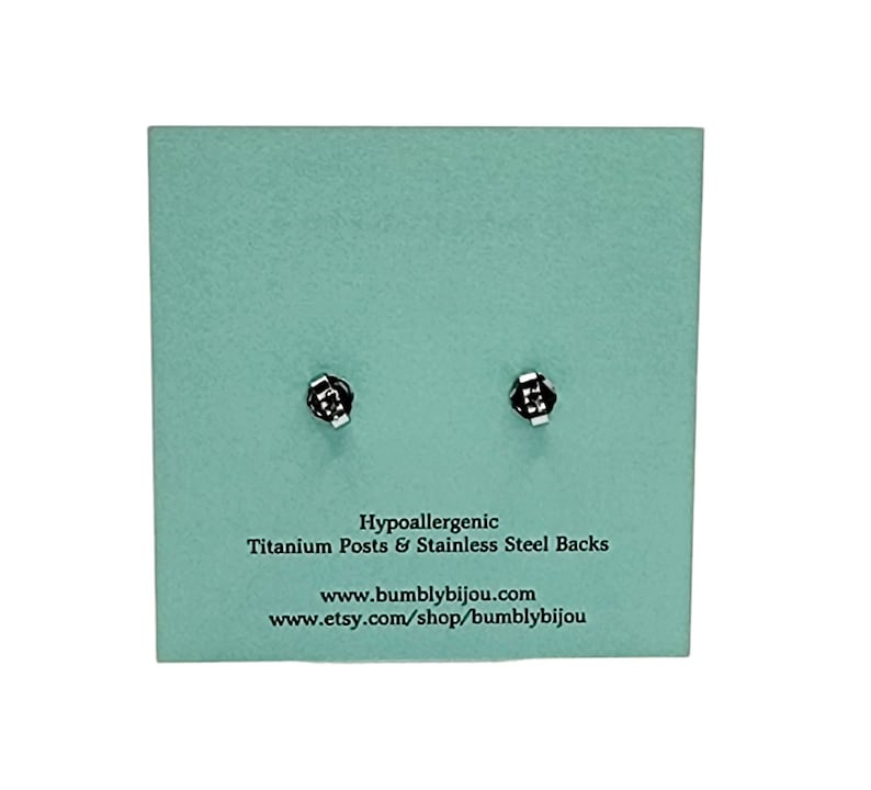 K&ouml;nnte beinhalten: Eine hellblaue Karte mit dem Text "Hypoallergenic Titanium Posts & Stainless Steel Backs" und der Website-Adresse "www.bumblybijou.com" und "www.etsy.com/shop/bumblybijou".