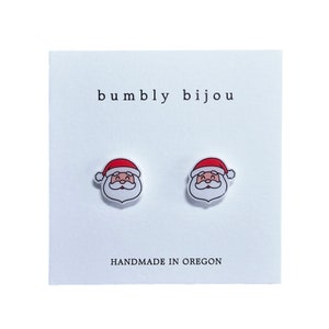 Peut inclure: Une paire de boucles d'oreilles clous blanches avec un motif de P&egrave;re No&euml;l rouge et blanc. Les boucles d'oreilles sont faites &agrave; la main dans l'Oregon et comportent le texte "bumbly bijou".