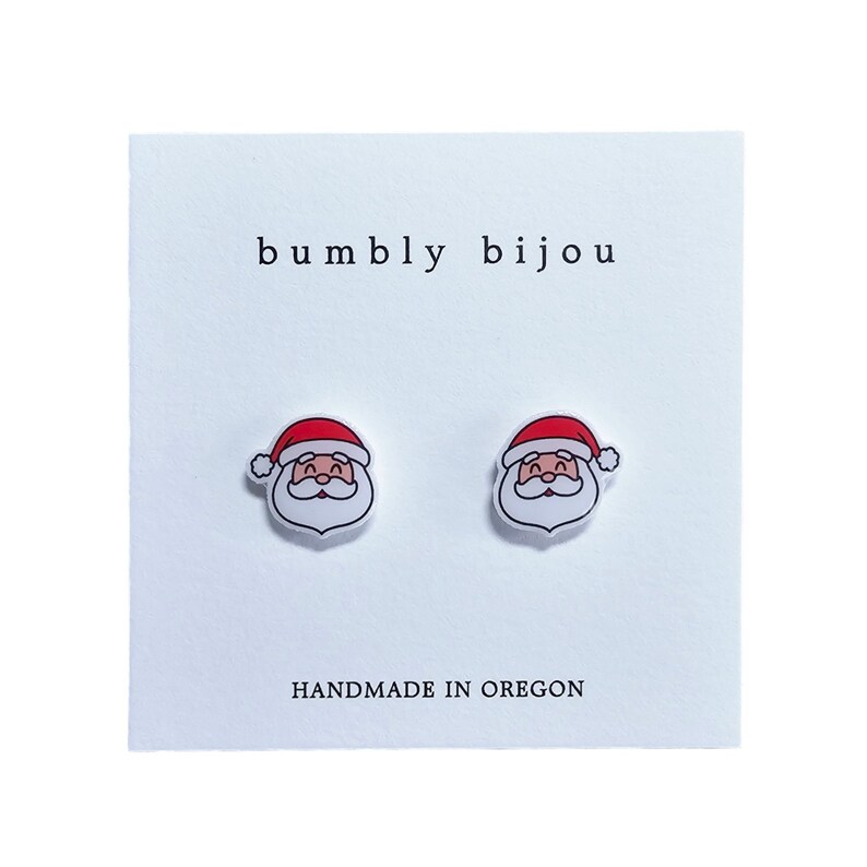 Peut inclure: Une paire de boucles d'oreilles clous blanches avec un motif de P&egrave;re No&euml;l rouge et blanc. Les boucles d'oreilles sont faites &agrave; la main dans l'Oregon et comportent le texte "bumbly bijou".