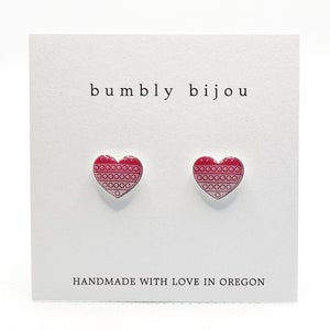 May include: A pair of pink and red heart-shaped earrings with a geometric pattern. The earrings are on a white card with the text "bumbly bijou" and "HANDMADE WITH LOVE IN OREGON".