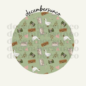 May include: A circular pattern featuring a repeating design of vintage cameras, suitcases, keys, pens, books, geese, and pink hearts on a green background. The text "decembersunco" is at the top.