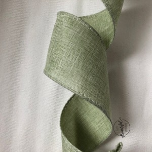 Peut inclure: Gros plan sur un ruban vert sauge avec un léger reflet. Le ruban a une apparence texturée, semblable au lin.