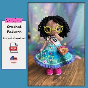 Puede incluir: Muñeca de ganchillo con cabello rizado negro, vestida con un vestido azul con mariposas bordadas, un pequeño bolso y zapatos rosas. La muñeca tiene gafas con montura verde. El texto a la izquierda dice "Crochet Pattern instant download PDF".