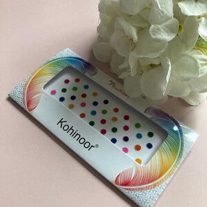 May include: A pack of colourful, round, adhesive, temporary, decorative, body jewels. The pack is white with a rainbow feather design and the text "New Phulkari" and "Kohinoor".
