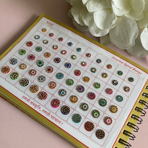 Könnte beinhalten: Ein Blatt mit bunten, runden, selbstklebenden Aufklebern mit goldener Umrandung und einem einzelnen Strassstein in der Mitte. Das Blatt ist mit "Assorted Spiral Range" und "हमारी संस्कृति, हमारी पहचान !" beschriftet.