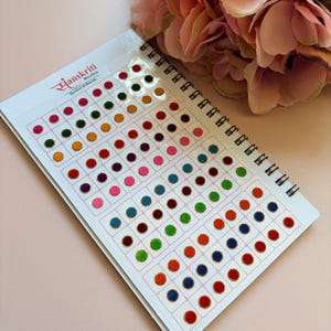 May include: A spiral-bound booklet containing a collection of small, circular adhesive bindis in various solid colours including red, green, orange, pink, blue, and purple. The cover features the text Sanskriti Bindies Symbol of Beauty.