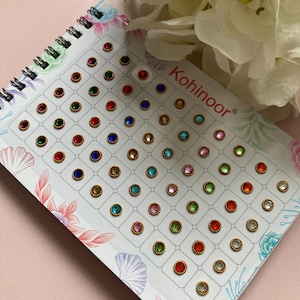 May include: A sheet of colourful adhesive rhinestones with a gold border. The sheet is labelled "Kohinoor".