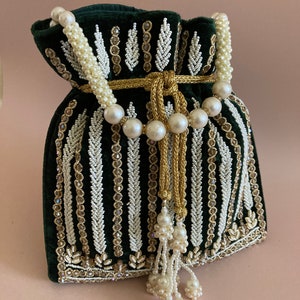 May include: A green velvet drawstring bag with white and gold beaded embroidery. The bag has a pearl and gold chain strap and a pearl tassel.