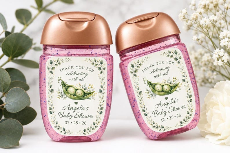 Two hand sanitizer bottles filled with pink glitter gel and topped with rose gold caps stand side by side, featuring custom pea pod labels.