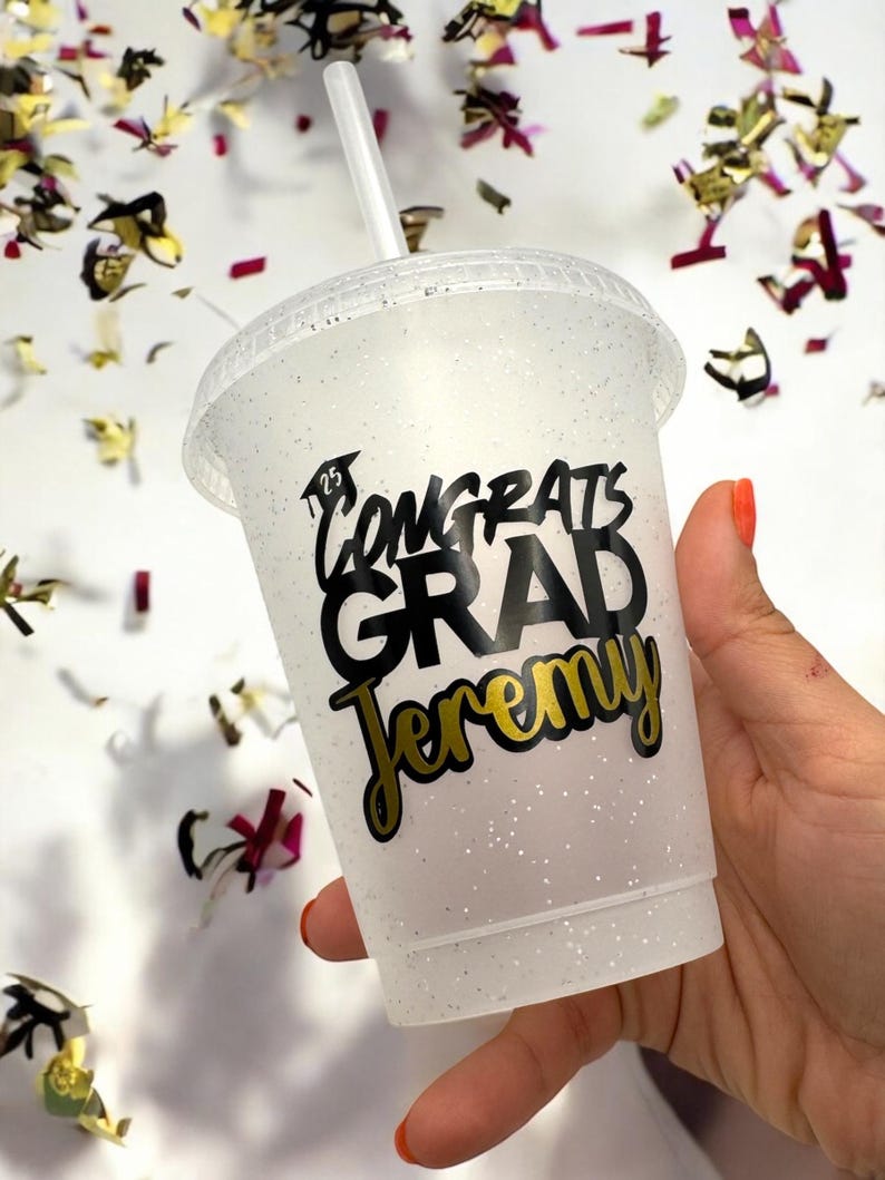 May include: White glitter tumbler with a black and gold sticker that says "Congrats Grad Jeremy".