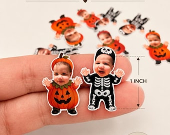 May include: A set of 50 pieces of 1-inch confetti featuring custom printed baby faces on illustrated bodies. The designs include babies dressed in orange pumpkin costumes and black skeleton outfits with white bone details, as shown in the image.
