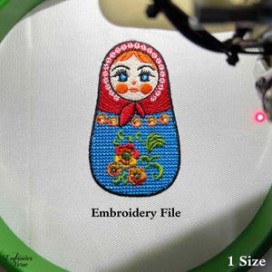 May include: Embroidery file of a blue and red Russian nesting doll with a floral design. The doll has a white face with blue eyes and red lips.