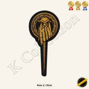 May include: Gold embroidered iron throne hand patch with a black background. The patch is 6 cm by 12 cm.