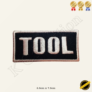 May include: Black embroidered patch with white lettering that reads "TOOL". The patch is 3.5 inches by 7.5 inches.