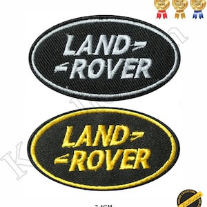 May include: Two black oval embroidered patches with white and yellow stitching. The patches feature the Land Rover logo with the text "LAND-ROVER". The patches are 7.4 cm in diameter.