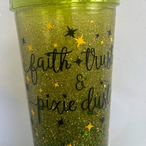 Peut inclure: Un gobelet vert &agrave; paillettes avec un motif &agrave; paillettes noires et dor&eacute;es. Le gobelet porte l'inscription "faith * trust & pixie dust".