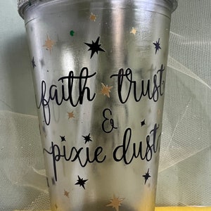 Peut inclure: Un gobelet en argent paillet&eacute; avec un motif noir et blanc qui dit "faith trust & pixie dust". Le gobelet est d&eacute;cor&eacute; d'&eacute;toiles dor&eacute;es paillet&eacute;es et d'une paille transparente.