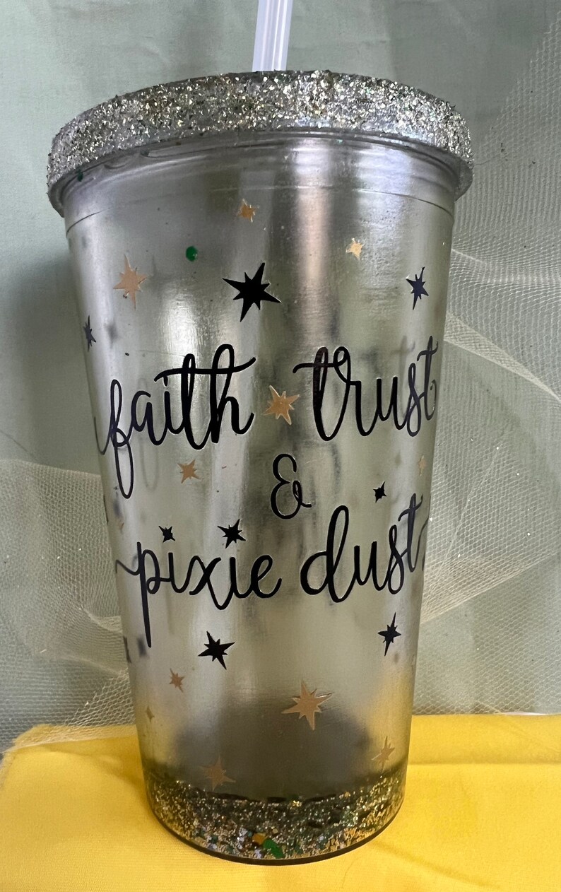 Peut inclure: Un gobelet en argent paillet&eacute; avec un motif noir et blanc qui dit "faith trust & pixie dust". Le gobelet est d&eacute;cor&eacute; d'&eacute;toiles dor&eacute;es paillet&eacute;es et d'une paille transparente.