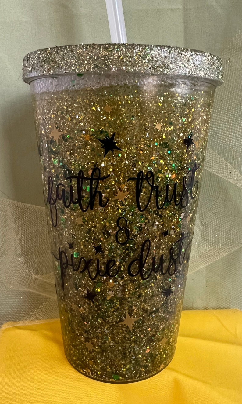 Peut inclure: Un gobelet en paillettes dor&eacute;es avec un design en vinyle noir qui dit "faith trust & pixie dust".