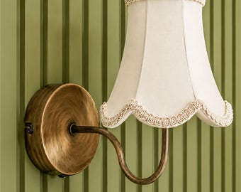 Vintage geïnspireerde wandlamp met gevoerde satijnen stoffen kap, geschulpte kap en antieke messing afwerking.