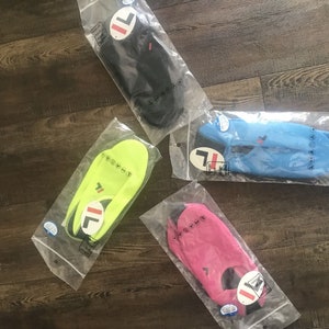 May include: Four pairs of water shoes in individual plastic packaging. The shoes are in black, blue, green, and pink. Each pair has a white "FILA" logo on the side.