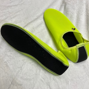 May include: A pair of neon yellow water shoes with black mesh and a black sole. The shoes have the text "Skin Socks" on the side.