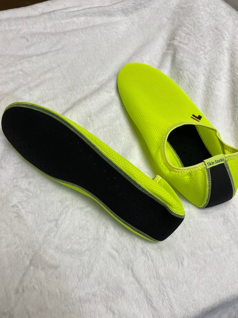 May include: A pair of neon yellow water shoes with black mesh and a black sole. The shoes have the text "Skin Socks" on the side.