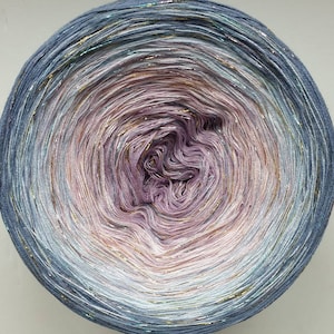 May include: A skein of yarn with a gradient of blue, purple, and white colours. The yarn has a subtle shimmer and is wound into a ball shape.