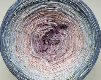 May include: A skein of yarn with a gradient of blue, purple, and white colours. The yarn has a subtle shimmer and is wound into a ball shape.